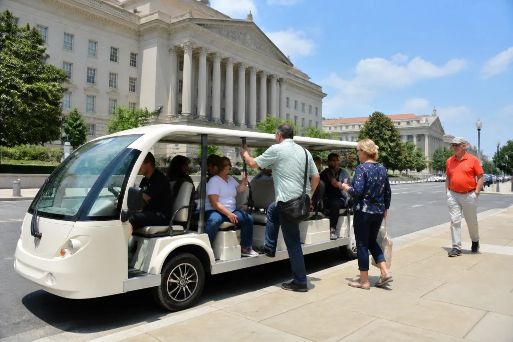 Passengers boarding an electric sightseeing cart at a paved curbside location in Washington DC.